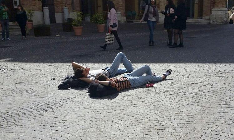 Due ragazzi si godono il primo sole di primavera in piazza a Macerata